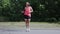 Slim beautiful girl in headphones dancing and having fun in park. Young woman in bright sportswear doing strange funny moves and f