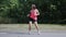 Slim beautiful girl in headphones dancing and having fun in park. Young woman in bright sportswear doing strange funny moves and f
