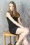 Slim beautiful red-haired girl in a black mini dress with a chair