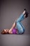 Slim beauty woman lying on a floor in jeans on grey backgro