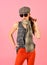 Slim blond model in tartan cap and scarf wearing big black sunglasses isolated on pink background
