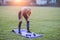 Slim blonde girl plays sports and performs yoga poses in summer grass covered stadium on a sunset background. Woman doing