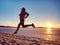 Slim body person is running. Beach sand with footprints