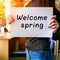 Slim brunette girl holding paper with Welcome Spring phrase in