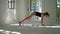 Slim caucasian woman standing on the mat in the large room practicing yoga. The girl standing in Downward Facing Dog