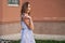 Slim european model in trendy blue dress walks along street