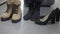 Slim female barefoot feet tapping with casual boots and formal high-heels standing on floor in shoe shop. Unrecognizable