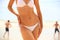 Slim female body in bikini and guys playing fresbee