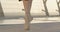 Slim female Caucasian legs in pointes standing up on tiptoes. Unrecognizable ballerina dancing on bridge at sunrise on