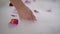 Slim female hand touching bath foam with red rose petals. Unrecognizable Caucasian young woman taking bath at home