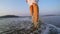 Slim female legs stepping at seaside surf.