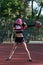Slim fit girl cheerleader with pink hair dancing outdoors with red and silver pompoms at the stadium
