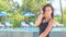 Slim girl in black smoothes hair approaches camera at pool