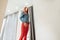 Slim girl with redheads chooses clothes. woman in red leather pants posing in fitting rooms. bottom view