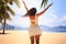 slim girl in white backside view poses with hands up on beach