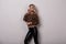 Slim glamorous young woman in a beautiful stylish leopard sweater in fashionable black leather pants poses in a studio