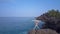 Slim lady makes hair bun standing on large stone by ocean