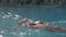 Slim lady in trendy red bikini swims in crystal blue pool