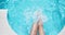 Slim legs close-up in clear blue water in the pool. A woman quickly moves her legs in the water, drops fly in different