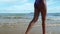 The slim legs of a tan skin model wear a bikini that walks on the beach in the summer.