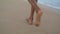 Slim legs walking beach at ocean waves closeup. Woman stroll leaving footprints