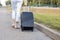 Slim legs of woman with suitcase walk along roadside of empty highway moving away while wait passing car. Lady escape