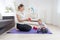 Slim mother with her baby son sitting on fitness mat at home and
