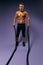 Slim muscular man training with battle rope