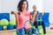 Slim sporty women training sitting on exercise balls holding dumbbells and squeezing Pilates Ring between their legs