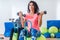 Slim sporty women training sitting on exercise balls holding dumbbells and squeezing Pilates Ring between their legs