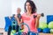 Slim sporty women training sitting on exercise balls holding dumbbells and squeezing Pilates Ring between their legs