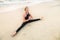 Slim strong middle age woman in black practicing yoga on sand beach