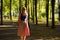 Slim tall girl with blond hair wearing sunglasses in a blue top and a light skirt walks in the Park. horizontal photography