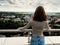 Slim teenager girl posing on top of a building with beautiful town in the background. Travel and tourism concept. Cloudy sky.