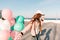 Slim trendy girl in stylish pink clothes walking along the ocean wharf enjoying windy morning in weekend. Charming young