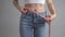 Slim woman in blue jeans measuring her perfect waist after successful weight loss