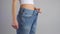 Slim woman in oversized jeans shows perfect waist after successful lost weight