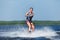 Slim woman riding wakeboard on wave of boat