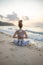 Slim yogi woman sitting in Padmasana  Lotus Pose on the beach. Hands in namaste mudra. View from back. Self care concept. Yoga