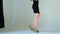 Slim young girl in a black dress and heeled shoes walks