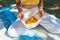 An slim young woman holds white headwear with lemons. Female in white pants and yellow jersey holding a cotton basket of fresh-