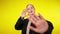 Slim young woman stretching hand at camera standing at yellow background. Portrait of beautiful Caucasian millennial