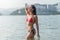 Slim young woman wearing bikini standing in sea with her eyes closed taking deep breaths enjoying fresh air, warm