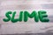 Slime text made from green slimeon a wooden table surface