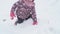 Slo-mo authentic happy preschool toddler baby girl in hat and mittens crawl on all fours in snow and falls on back