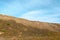 The slope of a clay hill against the backdrop of a beautiful blue sky. Lifeless soil. Sunny weather. Landscape