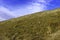 The slope of a clay hill against the backdrop of a beautiful blue sky. Lifeless soil. Sunny weather. Landscape