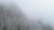 Slope of mountain in mist. Shot. Dense gray fog envelops entire space. Top view of rock plunging into cold autumn fog