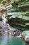 Slope overgrown with ivy and moss with flowing little waterfall