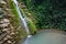 Slope overgrown with ivy and moss with waterfall flowing down